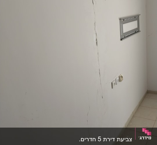 קיר עם סדק ותיקוני צבע על הרצפה
